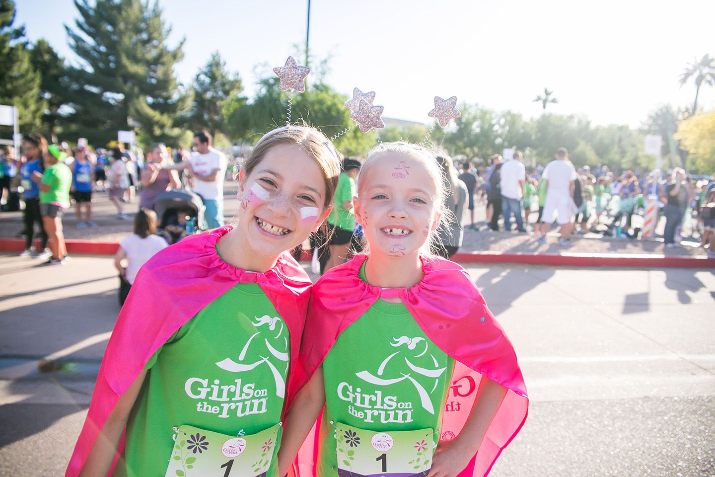 two Girls on the Run participants smile in green GOTR shirts with pink capes